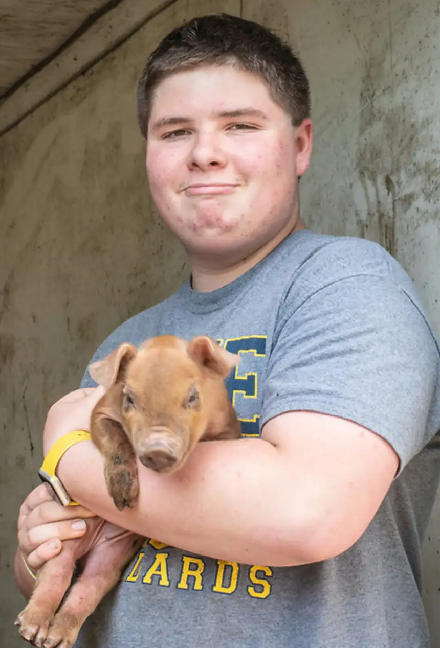 Young man in a doorway holding a piglet